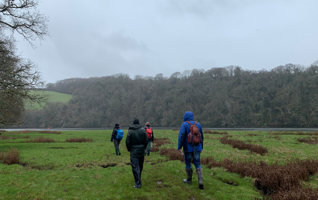 Image of four people walking in the rain through fields
