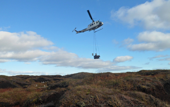 a helicopter airlifting materials across a peatland.