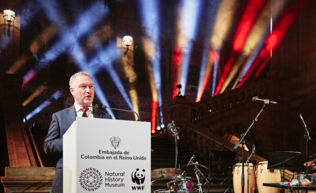 image of Steve Reed speaking at an event. Steve is in the foreground on the left hand side, standing at a podium.