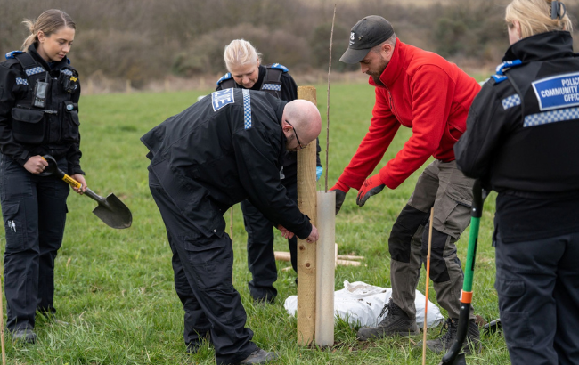 A photo of police officers in uniform helping with tree planting